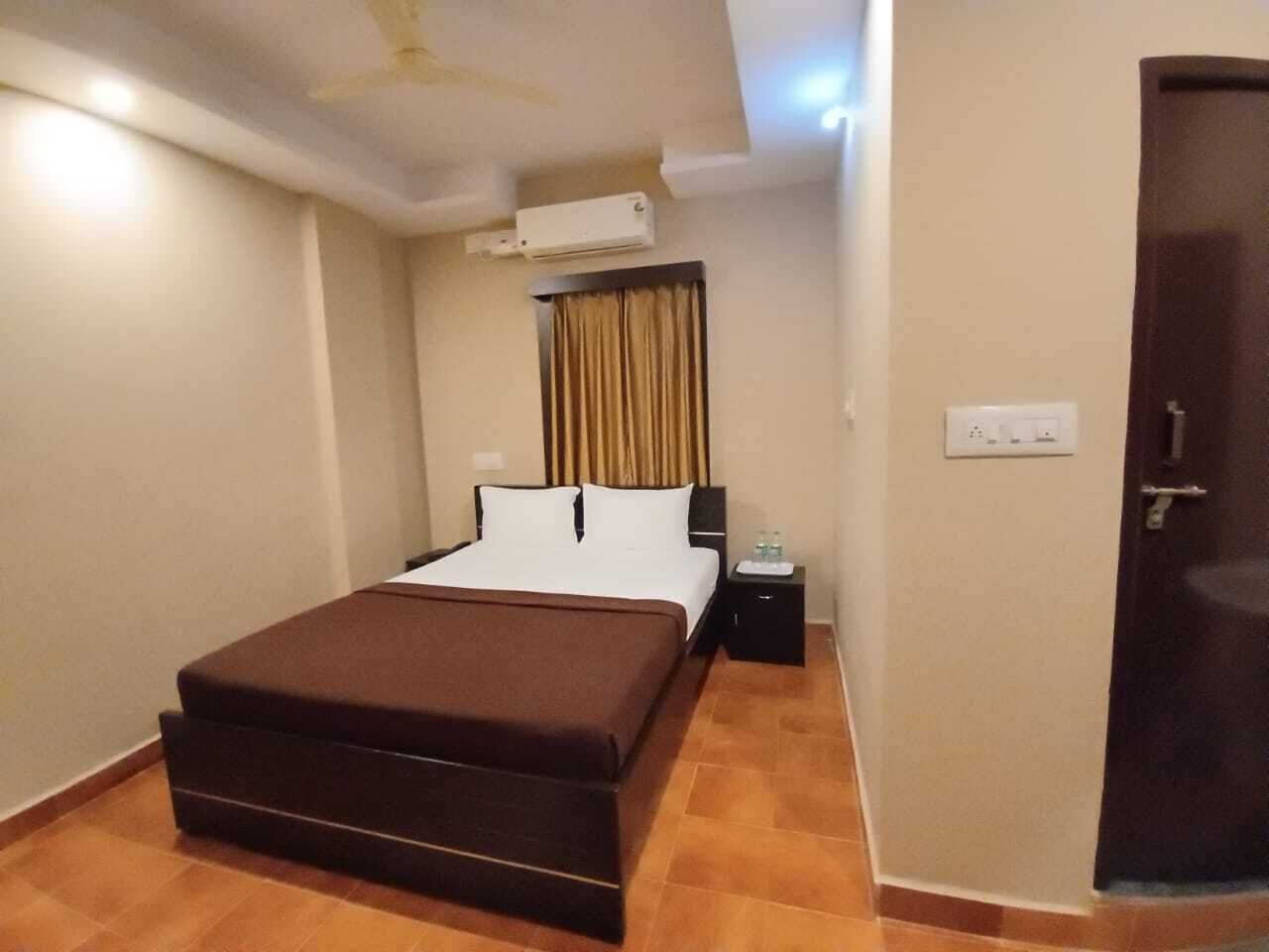 Une chambre d’hôtel avec un lit, une table de chevet, un appareil de climatisation et une porte.