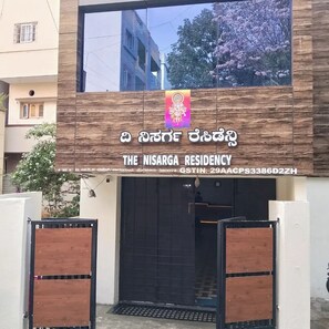 The exterior of The Nisarga Residency with a modern facade, a large entrance gate, and a visible street view. - The Nisarga residency  (Bengaluru)