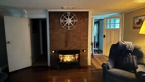 Ein Wohnzimmer mit Kamin, einem Ledersessel und einem großen Teppich.