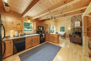 A wooden cabin with a kitchen, dining area, and living room. - The Hidden Gem | Hocking Hills, Log Cabin, Hot Tub (Logan)