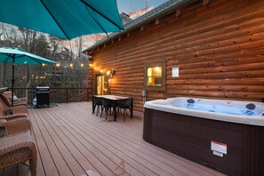A wooden cabin with a hot tub, outdoor seating, and string lights. - The Hidden Gem | Hocking Hills, Log Cabin, Hot Tub (Logan)