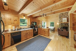 A wooden cabin with a kitchen, dining area, and living room. - The Hidden Gem | Hocking Hills, Log Cabin, Hot Tub (Logan)