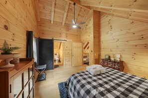 A wooden cabin bedroom with a bed, dresser, and ceiling fan. - The Hidden Gem | Hocking Hills, Log Cabin, Hot Tub (Logan)