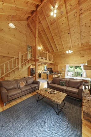 A wooden interior with a sofa, coffee table, and a staircase. - The Hidden Gem | Hocking Hills, Log Cabin, Hot Tub (Logan)