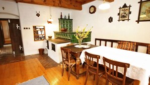 Un comedor con una mesa de madera, sillas, un armario verde y un reloj en la pared.