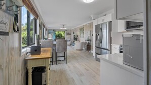 A modern kitchen with a central island, built-in appliances, and a dining area with wicker chairs.
