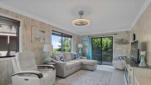 A modern living room with a sectional sofa, a white armchair, and a small table with lamps.