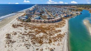 An aerial view of a coastal town with a beach, a marina, and residential buildings.