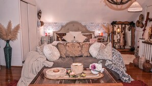 Een knus slaapkamer met een groot bed, een houten salontafel met decoratieve objecten, en een kroonluchter.