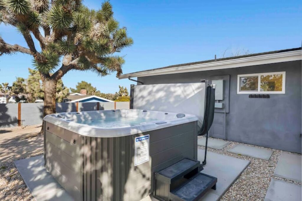 A hot tub in front of a building with a small window and a door.