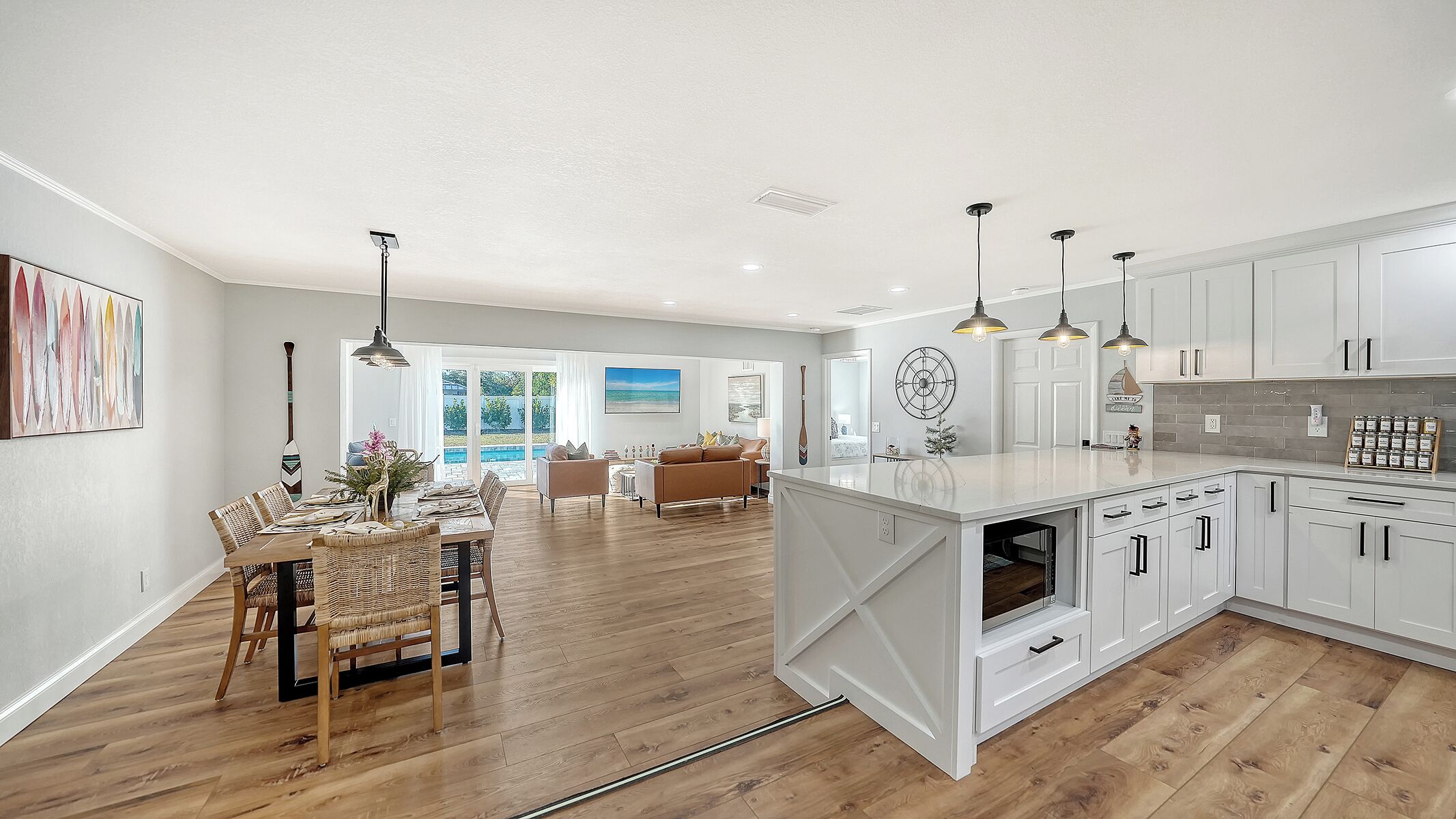 A spacious kitchen with white cabinets, a large island, and pendant lighting.