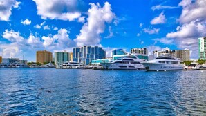 A marina with several yachts docked, surrounded by high-rise buildings under a partly cloudy sky. - Heated Pool Retreat • 3BR • Minutes to Siesta Key & Downtown (Sarasota)