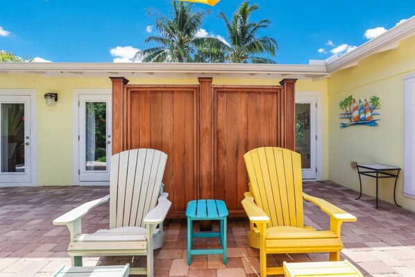 A patio with two Adirondack chairs, a small stool, and a table.