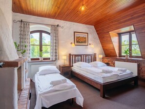 Ein gemütliches Schlafzimmer mit zwei Betten, Holzboden, großen Fenstern und einem Gemälde an der Wand.