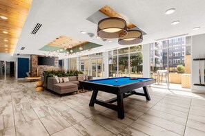 Un espacio interior amplio con mesa de billar, asientos cómodos y ventanas grandes que ofrecen vistas al exterior.