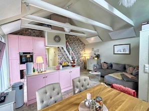 A compact living space with a kitchenette, a dining area, and a seating area with a sofa and a chair.