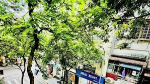 A street view with a Mini Mart sign, a storefront named 'SONG NUT', and a white car parked on the side of the road. - Autumn Hanoi House Bat Su (Hanoi)