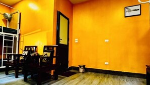 A room with orange walls, a wooden floor, a bunk bed, and a dining table with chairs. - Autumn Hanoi House Bat Su (Hanoi)
