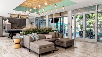 A modern living area with a sectional sofa, a pool table, and a dining area with outdoor seating.