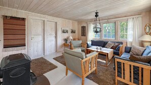 En hyggelig stue med trævægge, en sofa, stole, et bord og en pejs.