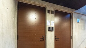 A set of elevator doors with a control panel and a small sign above the right door. - UNIFY 203 (Sapporo)