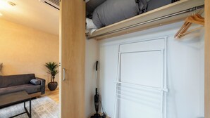A compact living space with a sofa, a small table, a potted plant, and a vacuum cleaner. - UNIFY 203 (Sapporo)