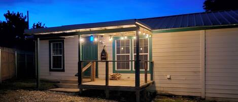 A small, single-story building with a porch and string lights.
