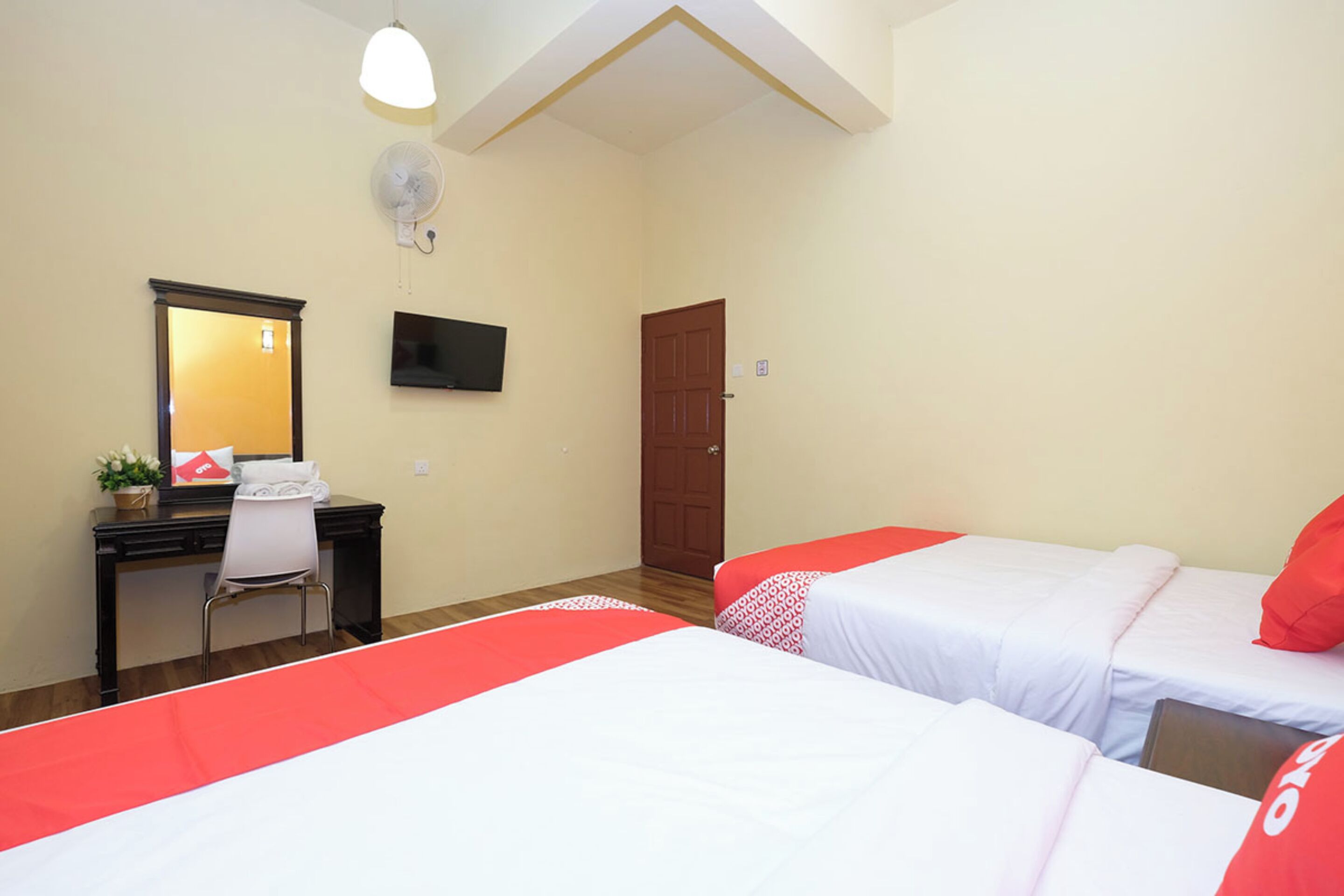 Een hotelkamer met twee bedden, een bureau, een stoel, een televisie en een deur.