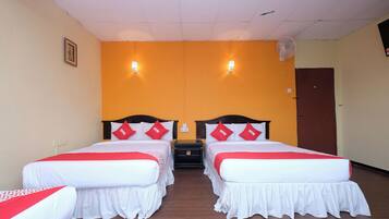 Habitación de hotel con dos camas, cada una con ropa blanca y almohadas rojas, y suelo de madera.