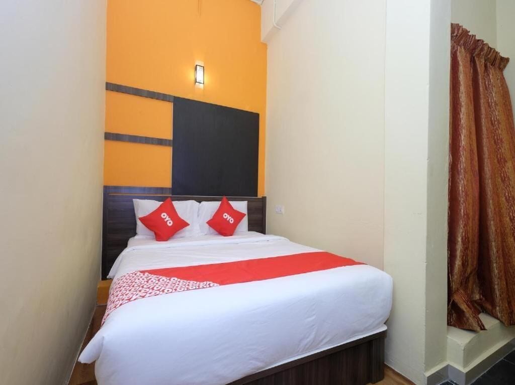 A hotel room with a bed, a headboard, and a window with curtains.