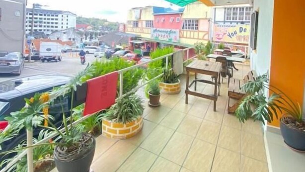 A balcony with potted plants, outdoor seating, and a view of the street. - Hotel Tudor Cameron Highland (Brinchang)