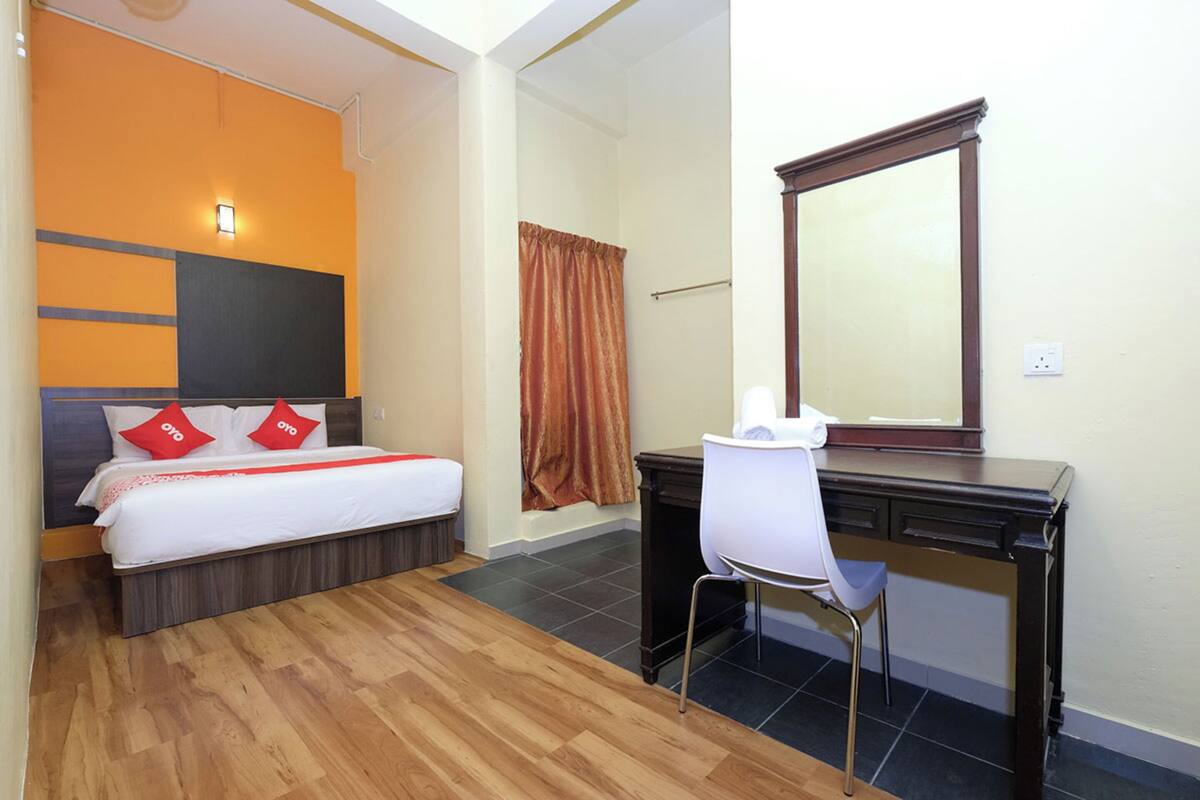 Una habitación de hotel con cama, escritorio y espejo.