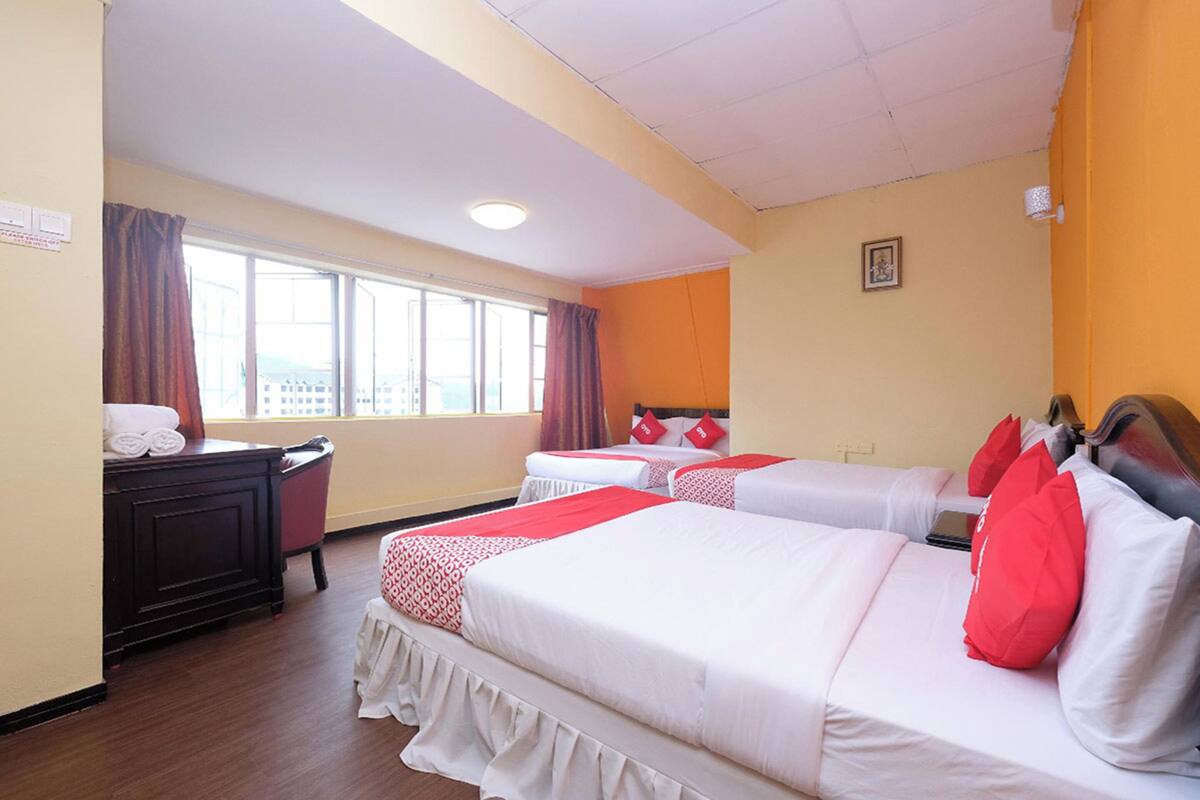 Una habitación de hotel con dos camas, un escritorio y un ventanal con cortinas.