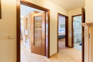 A hallway with wooden doors leading to a bedroom and a bathroom.