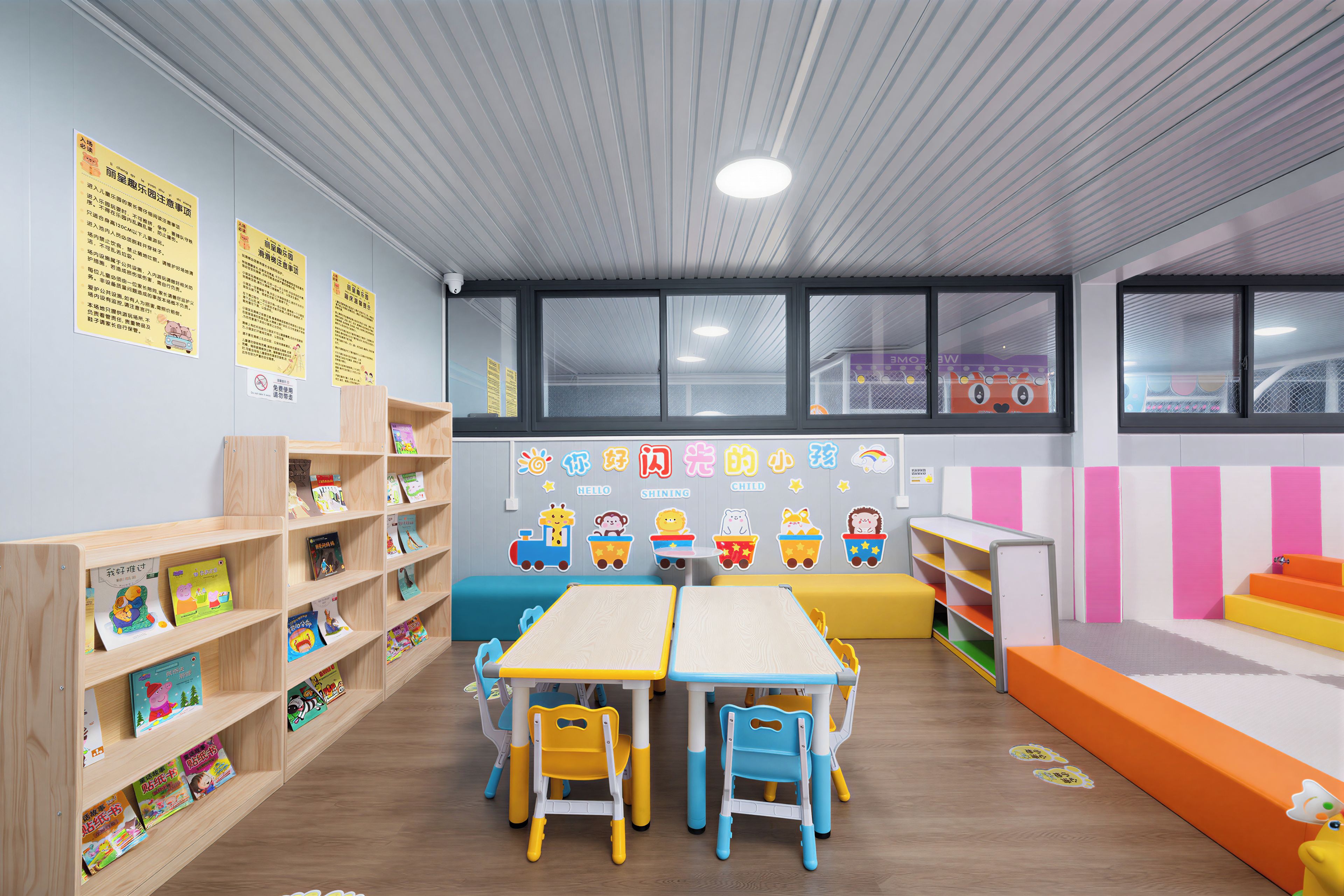 A children's playroom with a table, chairs, shelves with books, and educational posters on the walls.