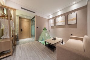 Quarto de hotel moderno com armário de madeira, uma tenda tipi verde e branca, um sofá bege, uma mesa pequena e obras de arte emolduradas na parede.