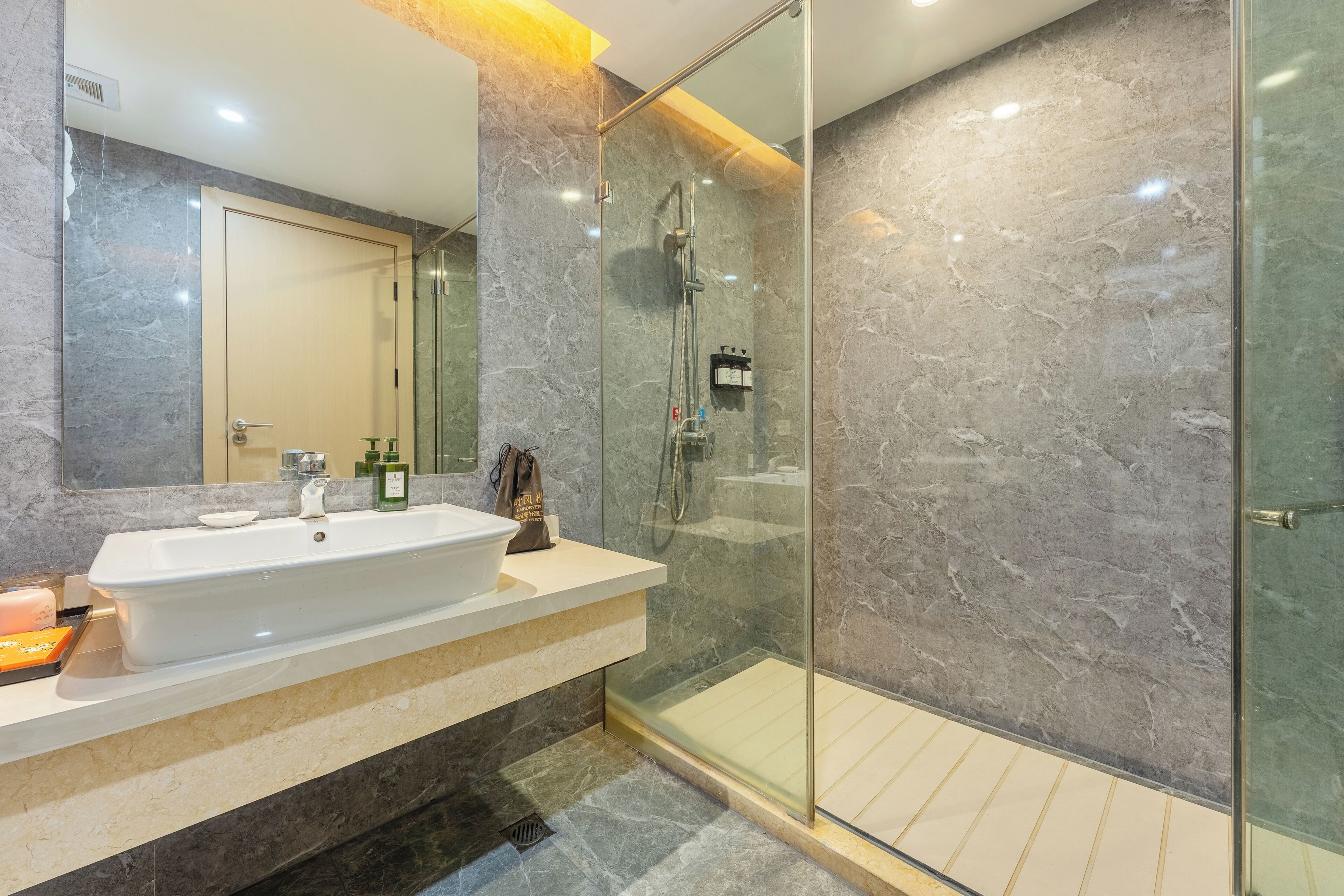 Ein modernes Badezimmer mit einem großen Waschbecken, einem Spiegel und einer Duschkabine aus Glas.