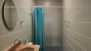 A bathroom with a sink, toilet, and shower area.