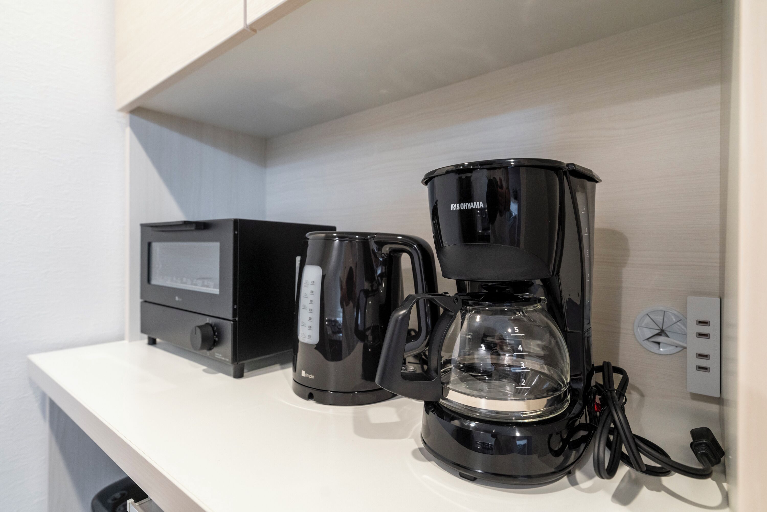 A coffee maker and a digital scale on a white countertop.