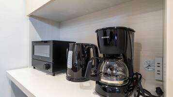 A coffee maker and a digital scale on a white countertop.