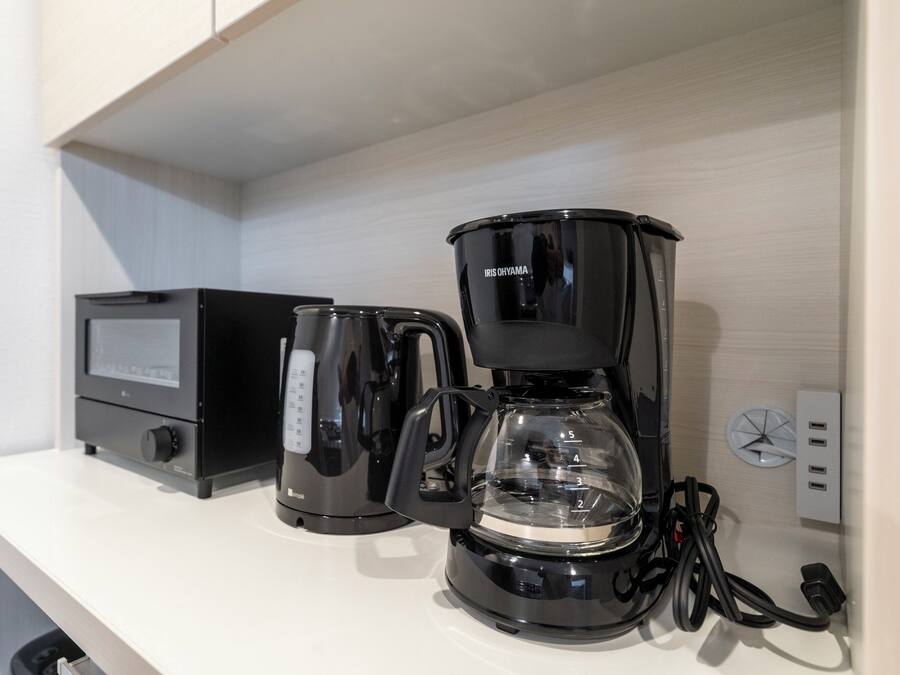 A coffee maker and a digital scale on a white countertop.