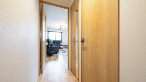 A hallway leading to a living area with a wooden door, a sofa, and a coffee table. - UNISON (Sapporo)