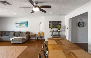A modern living room with a sofa, a dining table, and a ceiling fan.