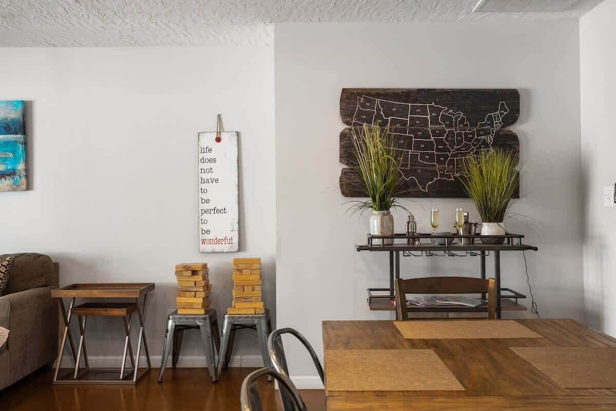 A dining area with a wooden table, chairs, a wall-mounted map, and a decorative sign.