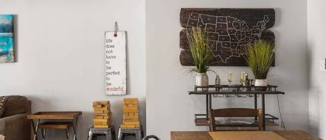 A dining area with a wooden table, chairs, a wall-mounted map, and a decorative sign.