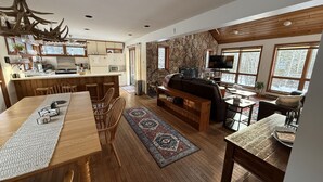 Amplia sala de estar con una mesa de comedor de madera, un sofá y un televisor.