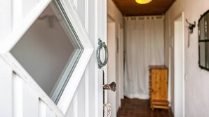 Un couloir avec une armoire en bois, une porte dotée d’une poignée en métal et un luminaire au plafond.