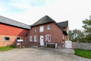 En byggnad av tegel med en vit dörr, vita fönster och en grusuppfart.
