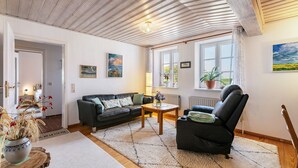 Un salon comprenant un canapé, un fauteuil, une table basse et une vue sur l’extérieur par une fenêtre.