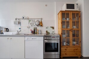 Een keuken met een magnetron, oven en verschillende keukengerei aan de wand.